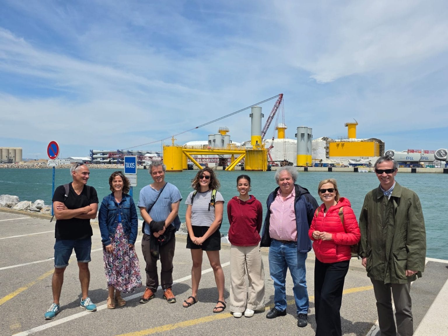 NiD4OCEAN team visits the Leucate pilot offshore wind project. Photo depicts the group during their visit. They are right next to the sea and far off we see turbines for offshore infrastructure being built